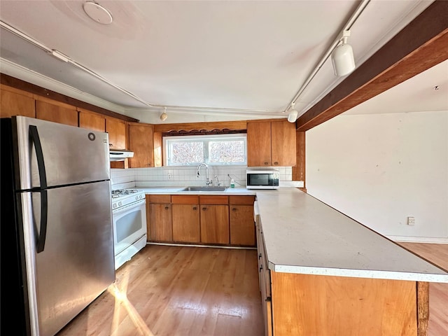 kitchen featuring sink, kitchen peninsula, white appliances, decorative backsplash, and light wood-type flooring