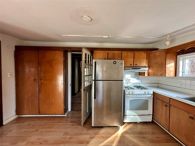 6 Hemlock Rd, South Salem, NY 10590 - kitchen featuring white range with gas stovetop, freestanding refrigerator, brown cabinetry, under cabinet range hood, and ornamental molding