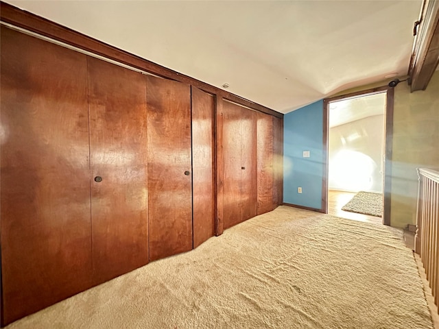 unfurnished bedroom featuring carpet floors, wooden walls, a closet, and lofted ceiling