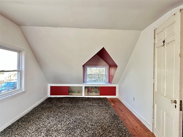 additional living space with hardwood / wood-style floors and vaulted ceiling