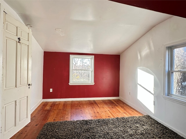 spare room with hardwood / wood-style floors and vaulted ceiling