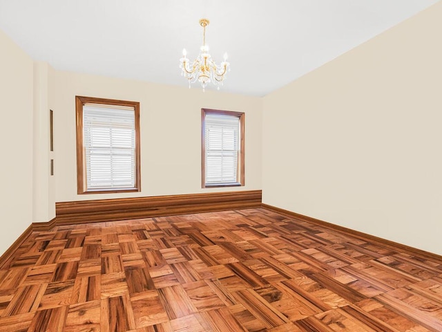 spare room with a notable chandelier and parquet flooring