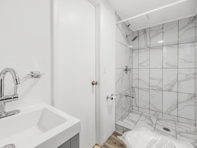 bathroom with a tile shower, hardwood / wood-style floors, and vanity