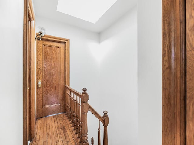 hallway with light wood-type flooring and a skylight