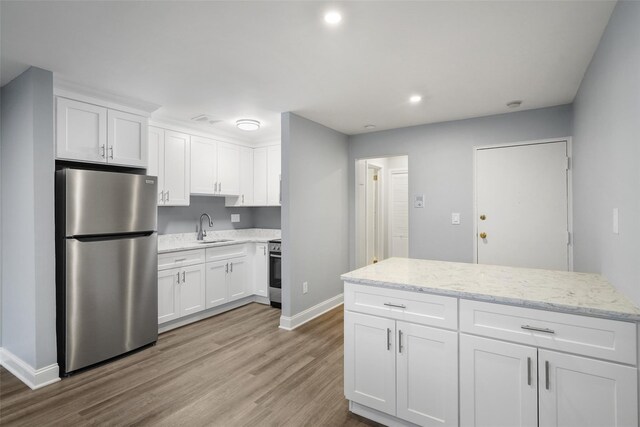 kitchen with a sink, freestanding refrigerator, light wood-style floors, white cabinetry, and range