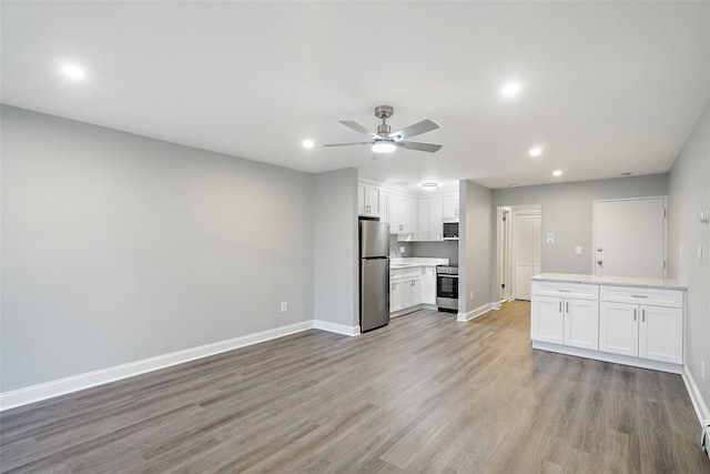 unfurnished living room with recessed lighting, ceiling fan, light wood-type flooring, and baseboards