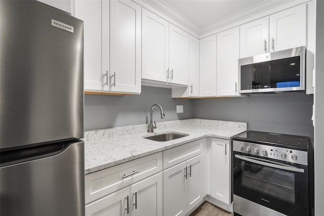 kitchen with a sink, white cabinets, appliances with stainless steel finishes, and light stone countertops