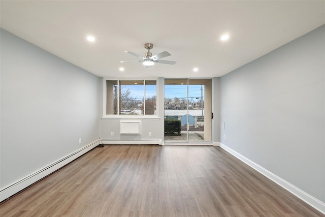 unfurnished room with baseboards, a ceiling fan, baseboard heating, wood finished floors, and a baseboard heating unit