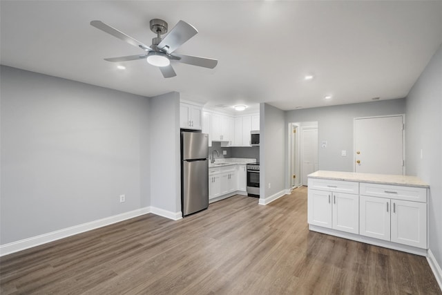 kitchen featuring wood finished floors, a sink, white cabinets, and stainless steel appliances