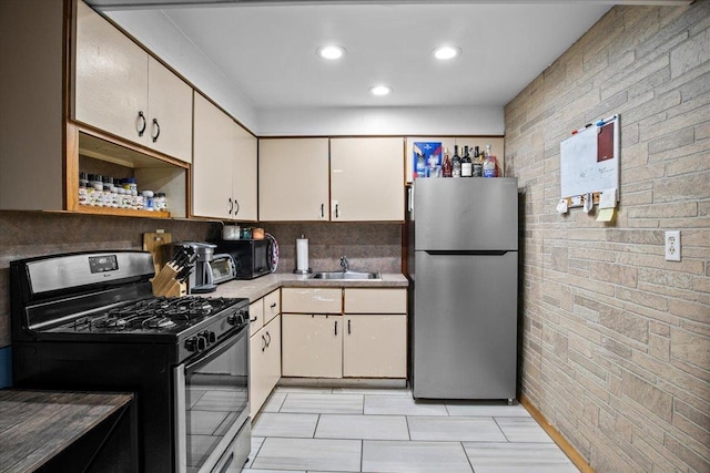 kitchen featuring cream cabinets, backsplash, stainless steel appliances, and sink