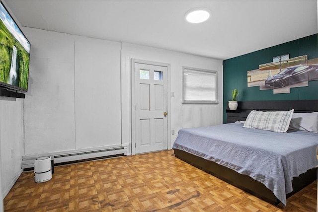 bedroom with a baseboard heating unit and light parquet flooring