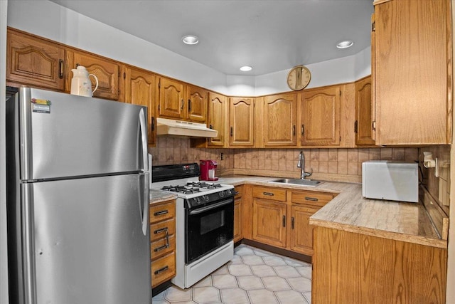 kitchen featuring stainless steel fridge, white range with gas stovetop, sink, and tasteful backsplash