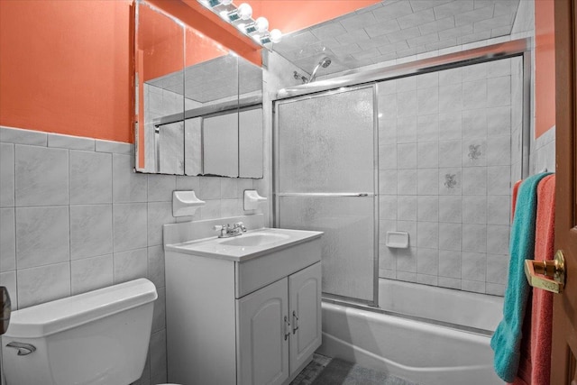 full bathroom featuring vanity, toilet, tile walls, and enclosed tub / shower combo