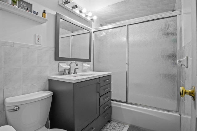 full bathroom with vanity, shower / bath combination with glass door, tile walls, tile patterned flooring, and toilet