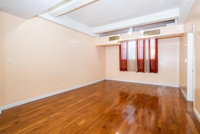 unfurnished room featuring beamed ceiling and wood-type flooring