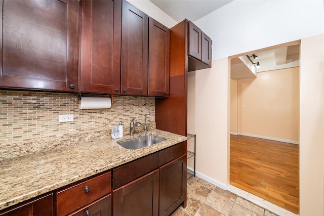 kitchen with decorative backsplash, light hardwood / wood-style floors, light stone countertops, and sink