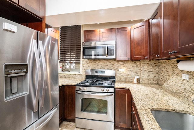 kitchen with sink, light stone counters, stainless steel appliances, and tasteful backsplash