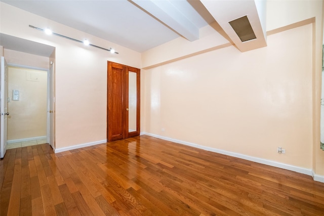 unfurnished room featuring hardwood / wood-style floors and beamed ceiling