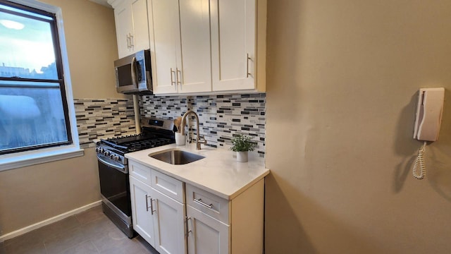 kitchen featuring backsplash, sink, white cabinetry, and stainless steel appliances