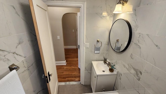 bathroom with hardwood / wood-style floors, vanity, and tile walls