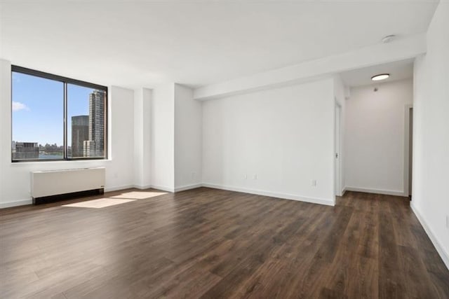 empty room featuring dark hardwood / wood-style flooring and radiator