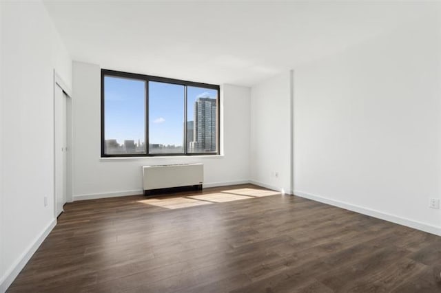 spare room with radiator heating unit and dark hardwood / wood-style flooring