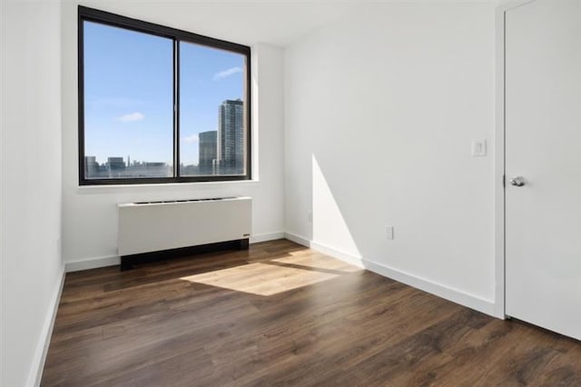 spare room with radiator heating unit and dark hardwood / wood-style floors