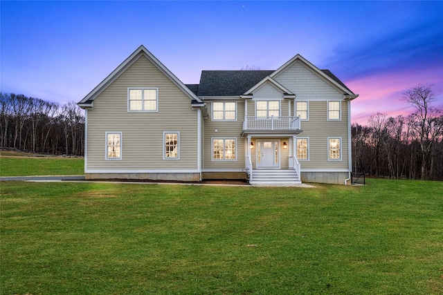 view of front of house featuring a balcony and a lawn