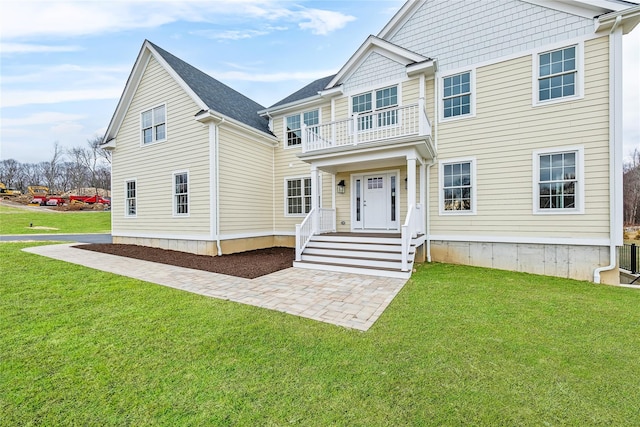 view of front of house featuring a balcony and a front lawn