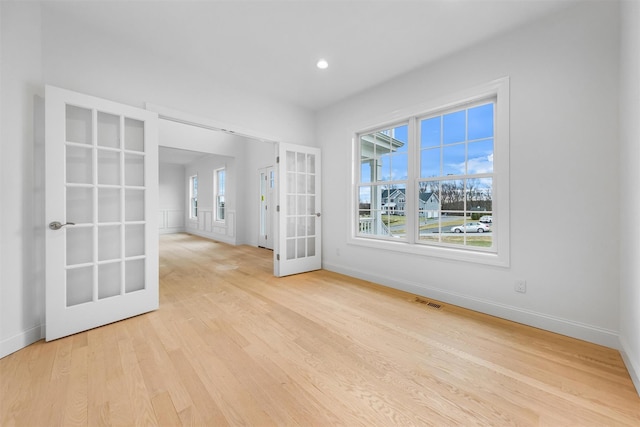 empty room featuring french doors and light hardwood / wood-style flooring