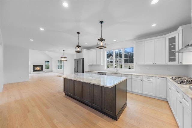 kitchen with appliances with stainless steel finishes, light wood-type flooring, white cabinetry, and sink