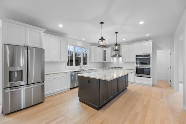 kitchen with stainless steel appliances, pendant lighting, white cabinetry, light hardwood / wood-style floors, and a kitchen island