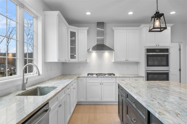 kitchen featuring white cabinetry, hanging light fixtures, wall chimney exhaust hood, and sink