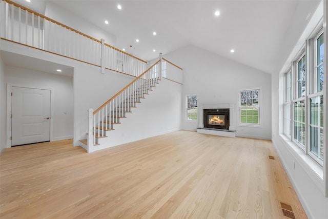 unfurnished living room featuring high vaulted ceiling and light hardwood / wood-style flooring