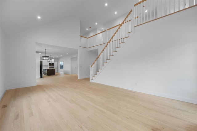 unfurnished living room with high vaulted ceiling and light hardwood / wood-style flooring