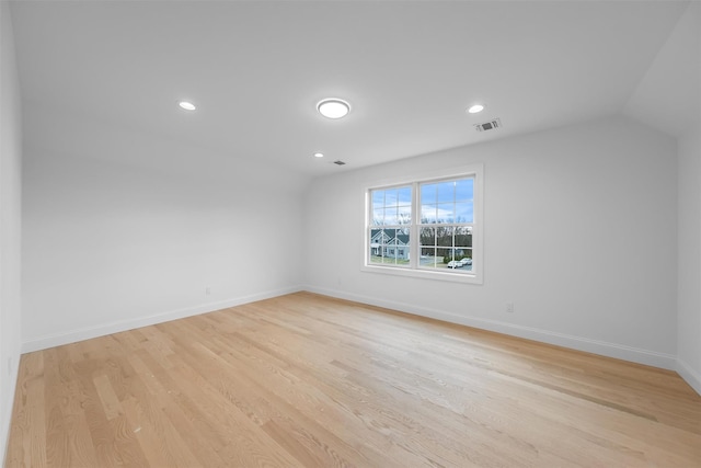 spare room featuring light hardwood / wood-style floors and vaulted ceiling