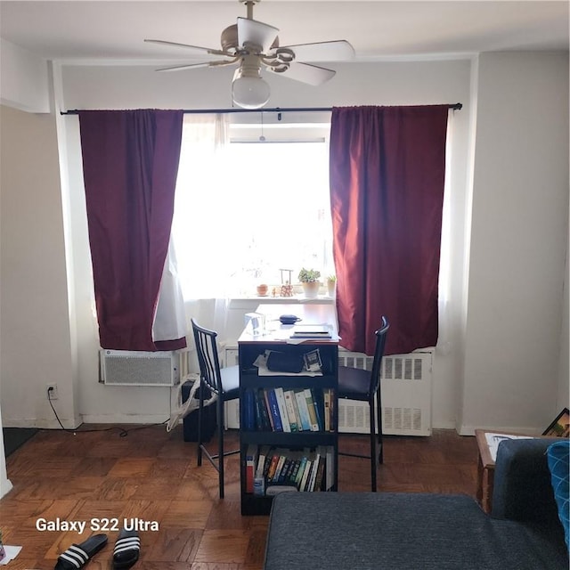 dining room with dark parquet flooring, ceiling fan, and radiator heating unit