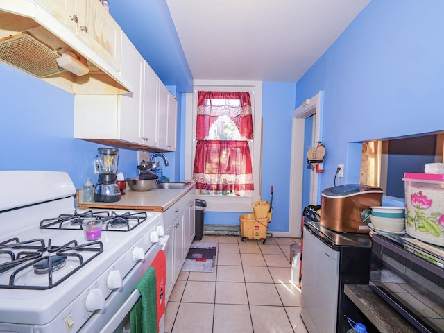 kitchen with white cabinets, white gas range, sink, and light tile patterned floors