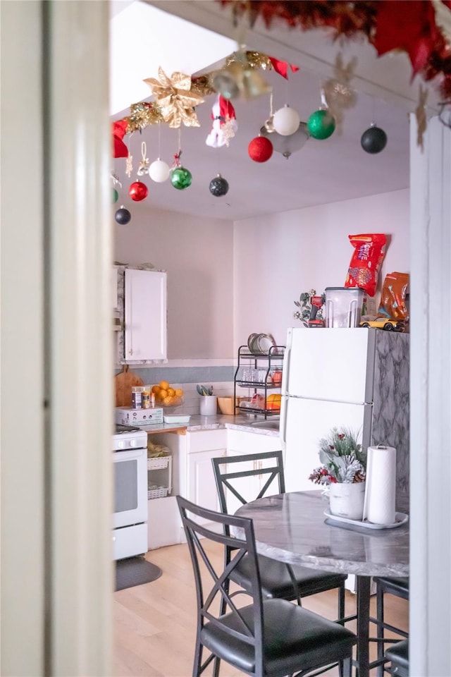 kitchen with light hardwood / wood-style flooring, white cabinets, and white appliances