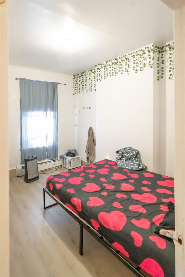 bedroom with hardwood / wood-style floors and a baseboard radiator