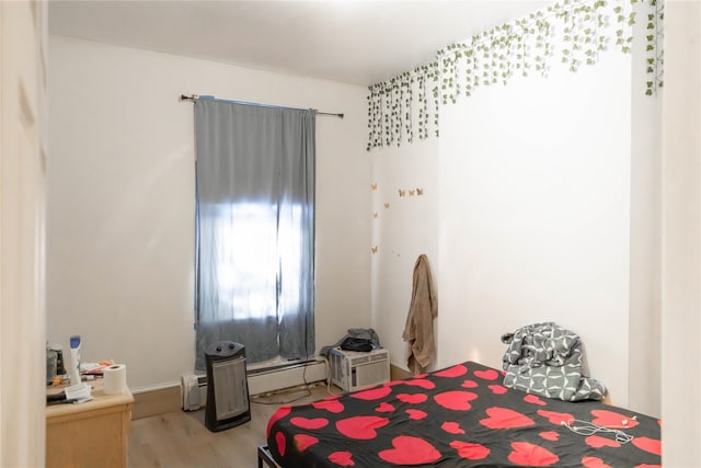 bedroom with baseboard heating and light wood-type flooring