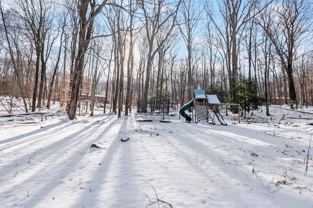 snowy yard featuring a playground