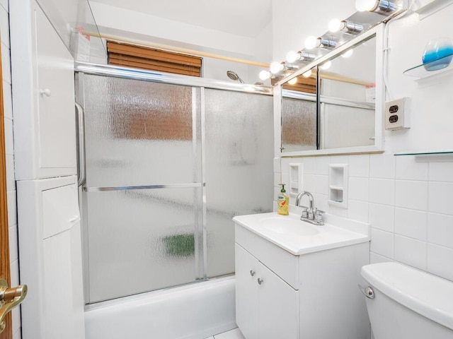 full bathroom featuring decorative backsplash, vanity, shower / bath combination with glass door, tile walls, and toilet