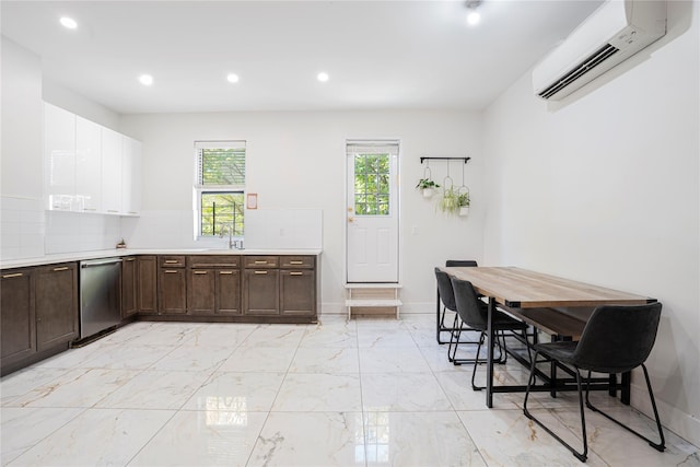 kitchen with dark brown cabinetry, white cabinetry, a wall mounted air conditioner, stainless steel dishwasher, and decorative backsplash