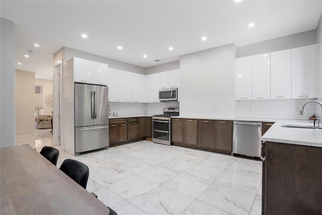 kitchen featuring decorative backsplash, dark brown cabinetry, stainless steel appliances, sink, and white cabinets