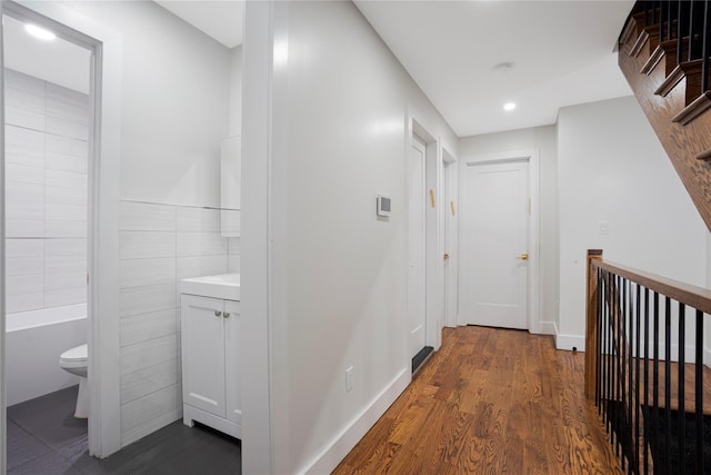 hallway featuring dark hardwood / wood-style floors and tile walls