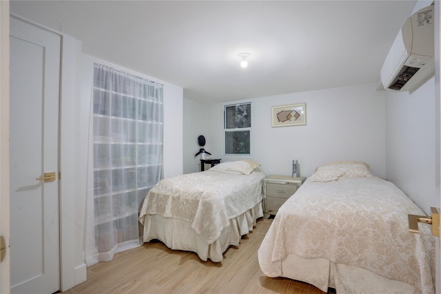 bedroom featuring a wall mounted air conditioner and light hardwood / wood-style floors