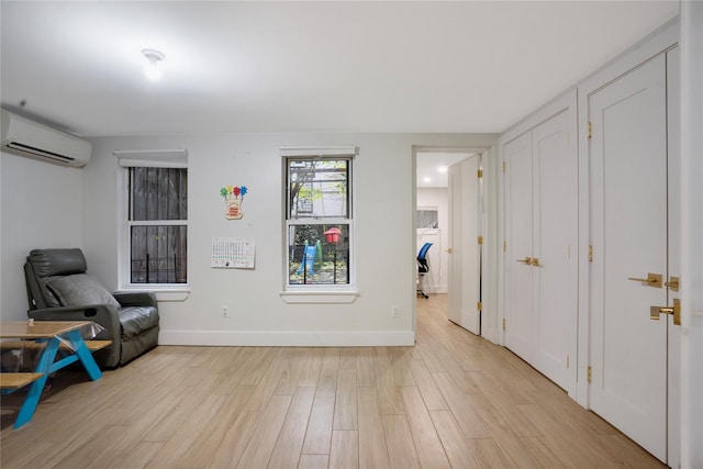 sitting room with light hardwood / wood-style floors and a wall mounted air conditioner