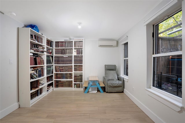 sitting room featuring a wall mounted air conditioner and light hardwood / wood-style floors