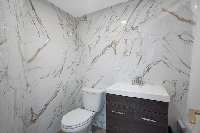 bathroom with vanity, toilet, and tile walls